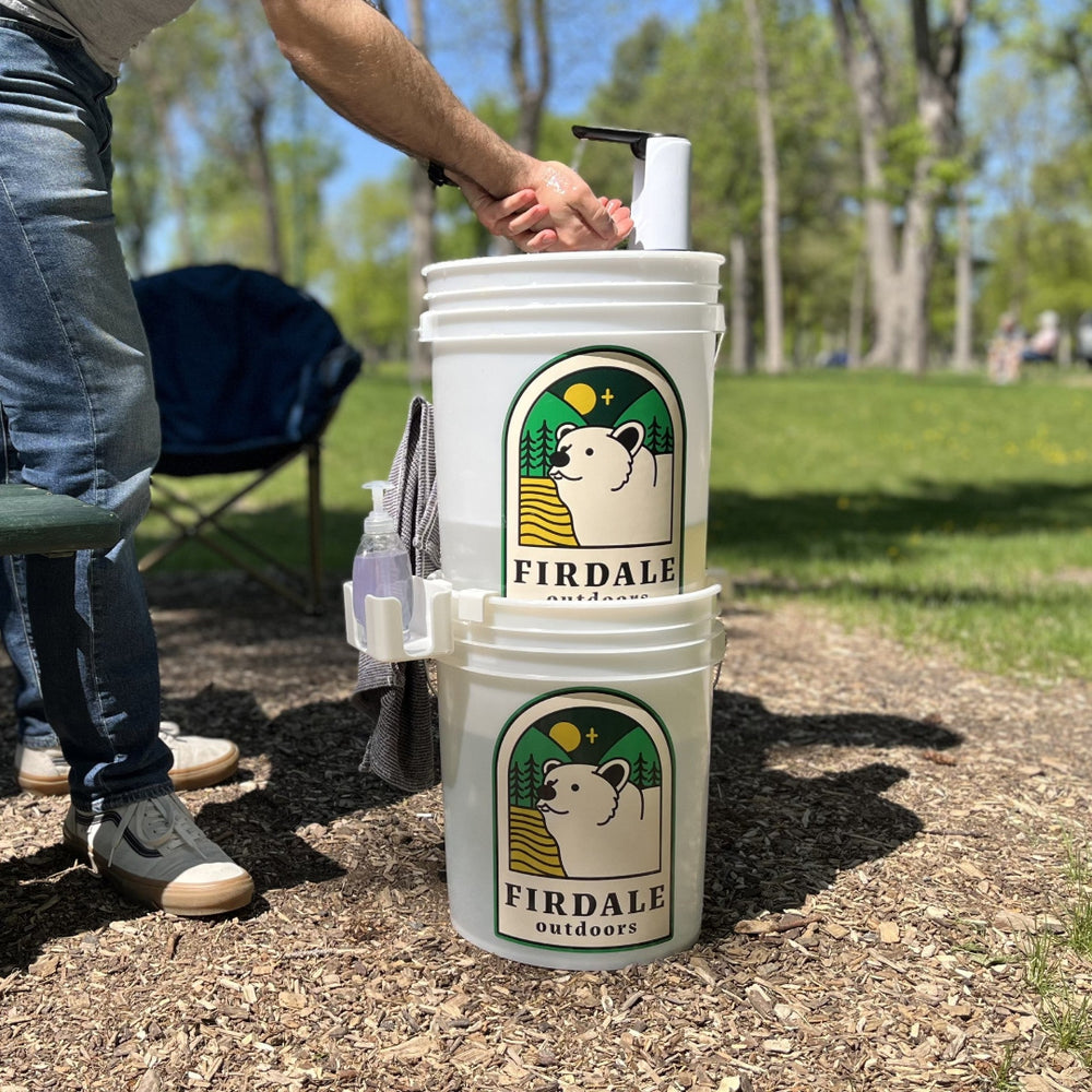 Two white buckets with Firdale Outdoors logo on a park ground.